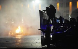 Un coche de la policía en llamas mientras la policía antidisturbios se prepara para detener a los manifestantes en el centro de Almaty, Kazajstán, el 5 de enero de 2022. (AP Photo / Vladimir Tretyakov)