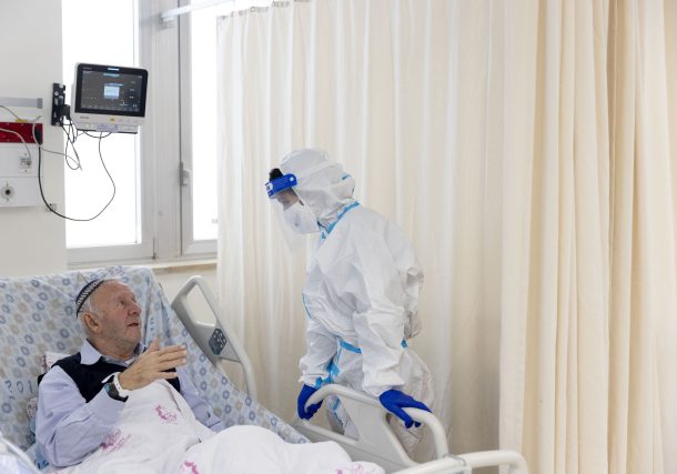 Un voluntario de Ezer Mizion con equipo de seguridad visita a un paciente en la sala de coronavirus del hospital Shaare Zedek en Jerusalén, el 20 de enero de 2022. (Olivier Fitoussi/Flash90)