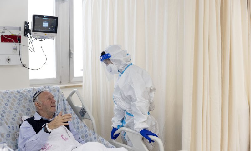 Un voluntario de Ezer Mizion con equipo de seguridad visita a un paciente en la sala de coronavirus del hospital Shaare Zedek en Jerusalén, el 20 de enero de 2022. (Olivier Fitoussi/Flash90)
