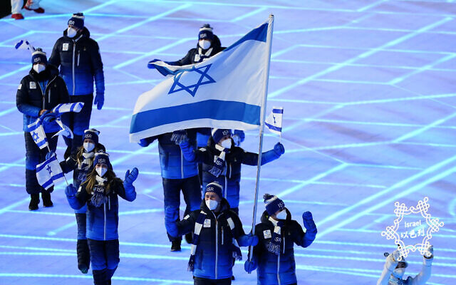 Evgeni Krasnopolski y Noa Szollos, de Israel, llevan su bandera nacional al estadio durante la ceremonia inaugural de los Juegos Olímpicos de Invierno de 2022, el viernes 4 de febrero de 2022 en Beijing. (Foto AP/Matt Slocum)
