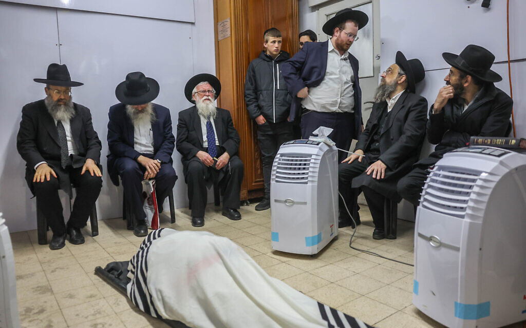 Familiares y parientes rezan mientras se reúnen alrededor del cuerpo del rabino Chaim Kanievsky, Bnei Brak, 20 de marzo de 2022 (Yonatan Sindel/ Flash90)