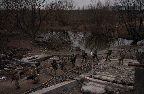 Soldados ucranianos cruzan un camino improvisado debajo de un puente destruido en Irpin, en las afueras de Kiev, Ucrania, el 12 de marzo de 2022. (AP/Felipe Dana)