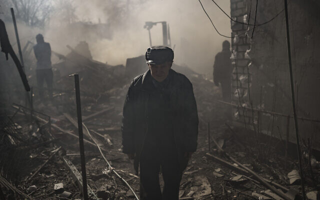 Un hombre camina en medio del humo de una casa en llamas, destruida después de un ataque ruso en Kharkiv, Ucrania, el 24 de marzo de 2022. (AP Photo/Felipe Dana)