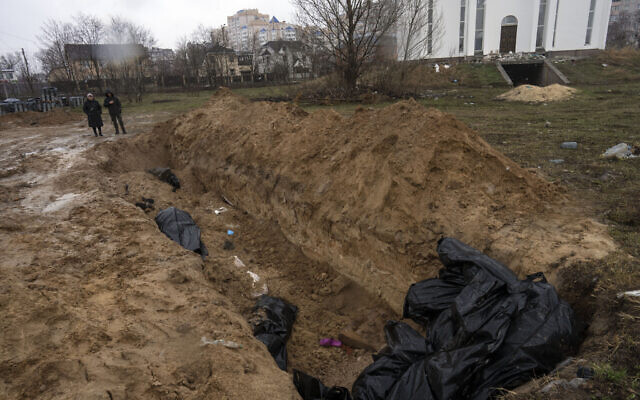 Los vecinos se reúnen junto a una fosa común en Bucha, en las afueras de Kiev, Ucrania, el 3 de abril de 2022. (Foto AP/Rodrigo Abd)