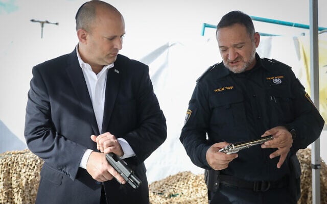 El primer ministro Naftali Bennett, a la izquierda, y el jefe de policía Kobi Shabtai observan las armas incautadas durante una visita a Rahat, en el sur de Israel, el 6 de diciembre de 2021. (Noam Revkin Fenton/Flash90)