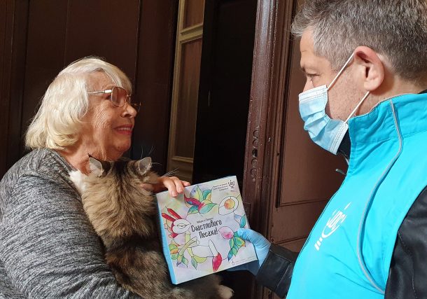Svetlana Niselevitch recibe una hagadá de Pésaj de un miembro del personal de JDC frente a su casa en Odessa, Ucrania, el 8 de abril de 2022. (JDC)