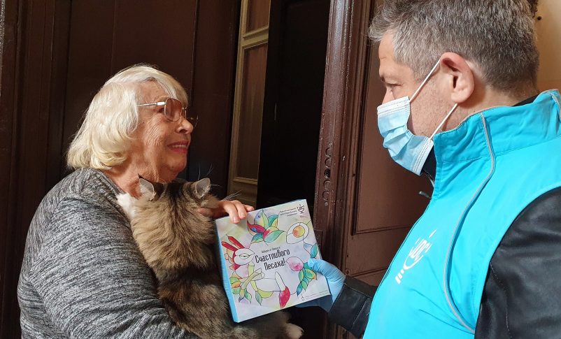 Svetlana Niselevitch recibe una hagadá de Pésaj de un miembro del personal de JDC frente a su casa en Odessa, Ucrania, el 8 de abril de 2022. (JDC)
