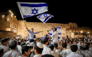 Hombres judíos bailan con banderas israelíes en el Muro Occidental en la Ciudad Vieja de Jerusalén en la víspera del Día de Jerusalén, 28 de mayo de 2022. (Noam Revkin Fenton/Flash90)