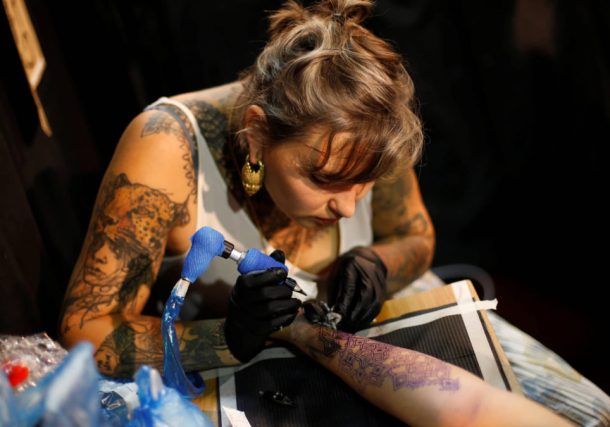 Un tatuador trabajando durante la Convención anual de tatuajes de Israel en Tel Aviv. (crédito: BAZ RATNER/REUTERS)
