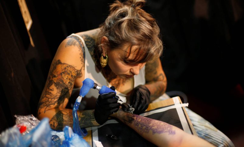 Un tatuador trabajando durante la Convención anual de tatuajes de Israel en Tel Aviv. (crédito: BAZ RATNER/REUTERS)