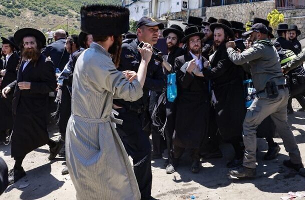 Los judíos ultraortodoxos se pelean con la policía cuando intentan ingresar a la tumba del rabino Shimon Bar Yochai en el Monte Meron, durante la festividad de Lag B'Omer que conmemora la muerte del erudito judío del siglo II, el 19 de mayo de 2022. (Menahem KAHANA / AFP)