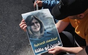 Radio Jai-Los palestinos sostienen un cartel que muestra a la veterana periodista de Al Jazeera Shireen Abu Aqleh, quien fue asesinada a tiros durante los enfrentamientos entre las tropas israelíes y los palestinos armados mientras cubría una redada de las FDI en el campo de refugiados de Jenin en Cisjordania el 11 de mayo de 2022, en la ciudad cisjordana de Hebrón. El cartel dice en árabe, "Martirio de la periodista Shireen Abu Aqleh". (HAZEM BADER / AFP)