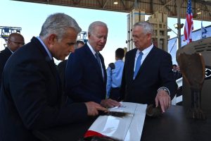 El ministro de Defensa, Benny Gantz, a la derecha, le entrega al presidente de los Estados Unidos, Joe Biden, el ala de un dron interceptado por el sistema de defensa láser Iron Beam, mientras el primer ministro, Yair Lapid (izq.), observa en el aeropuerto Ben Gurion, el 13 de julio de 2022. (Ariel Hermoni/Ministerio de Defensa)