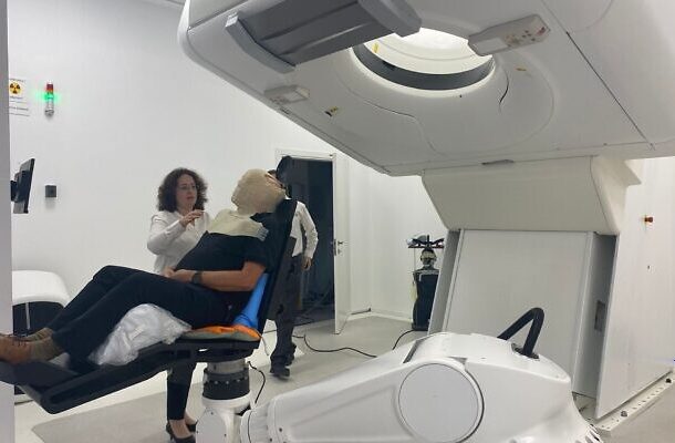 Radio Jai -La nueva instalación para la terapia de protones en el Centro Médico Hadassah en Jerusalén; un paciente en una silla usa una máscara de plástico que cubre la cara para protegerla de la radiación (Cortesía del Centro Médico Hadassah)