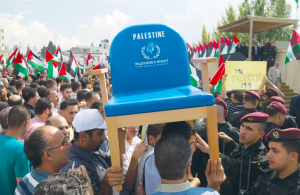 Radio Jai -LOS PALESTINOS LLEVAN una silla que representa su escaño en las Naciones Unidas durante una manifestación en Ramallah tras el regreso de Mahmoud Abbas de la Asamblea General de la ONU después de una candidatura a la condición de Estado en septiembre de 2011. (Crédito: Darren Whiteside/Reuters)