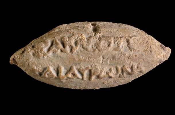 Radio Jai -Los nombres de los dioses Heracles y Hauron en el reverso de una bala de honda encontrada en Yavne. (Dafna Gazit/Autoridad de Antigüedades de Israel)