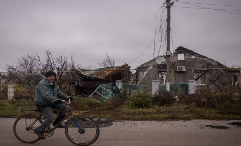 Radio Jai -Un hombre pasa en bicicleta frente a una casa destruida en el pueblo de Posad Pokrovske, en las afueras de Kherson, Ucrania, el 30 de noviembre de 2022. (Chris McGrath/Getty Images)