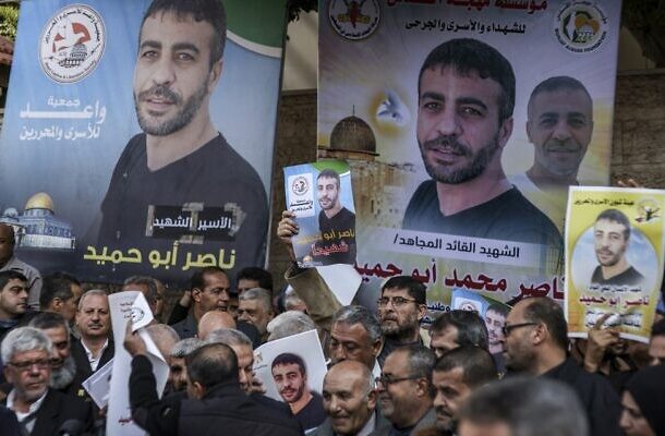 Radio Jai -La gente se reúne con fotos del palestino Nasser Abu Hmeid para una protesta frente a la sede de la misión del Comité Internacional de la Cruz Roja (CICR) en la ciudad de Gaza el 20 de diciembre de 2022. (Mahmud HAMS / AFP)